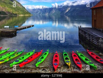 Kajaks aufgereiht entlang der Küste in einem Fjord in Norwegen Stockfoto