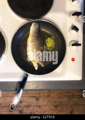 Wolfsbarsch Fisch Filet in der Pfanne mit Knoblauch Butter Stockfoto