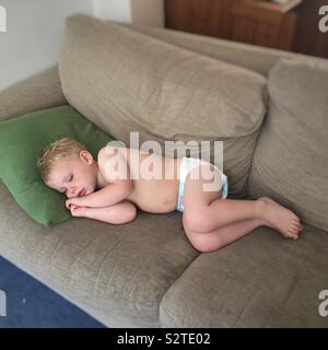 Zwei Jahre alten Sohn schläft auf dem Sofa bei dem heißen Wetter. Hampshire, England, Vereinigtes Königreich. Stockfoto