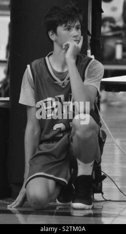 Spiel Zeit, Teenager auf einem Knie warten Zurück im Basketball Spiel zu gehen Stockfoto