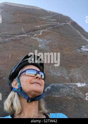 Eine weibliche Radfahrer schiefen und entspannende gegen einen Felsen. Stockfoto