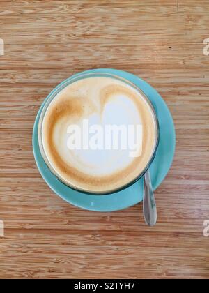 Latte in einem Glas auf einem grünen Untertasse Stockfoto