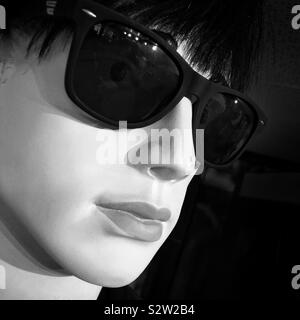 Eine schwarze und weiße Nahaufnahme einer männlichen Puppe im Profil Wer trägt dunkle Sonnenbrille Stockfoto