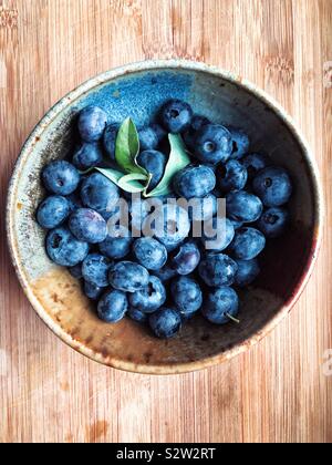 Frisch gepflückte Blaubeeren in Steinzeug Schüssel auf Bambus board Stockfoto