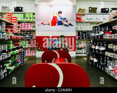 Schwester und Bruder aufpassen Bildschirm bei Deichmann Schuhgeschäft Rückansicht Stockfoto