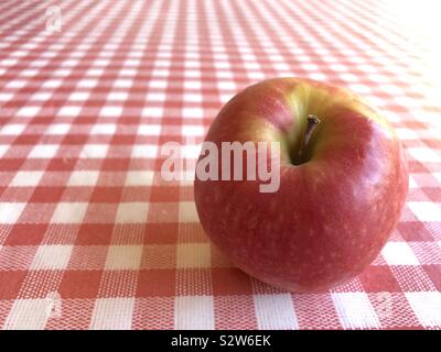 Red Apple auf einer rot-weiß karierten Hintergrund Stockfoto