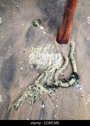 Eine gebrochene Festmacher Seil auf den Strand verlassen, mit Sand durch verschmutztes Grundwasser verfärbt, Straße von Malakka, in der Nähe von Lumut, Perak, Malaysia Stockfoto