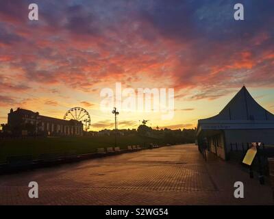 Breaking Dawn über Barry Island Kirmes und Promenade, South Wales. Stockfoto