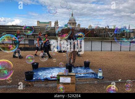 Street Hersteller/Gaukler Seifenblasen entlang der Themse mit St. Pauls Kathedrale im Hintergrund - London, Großbritannien Stockfoto