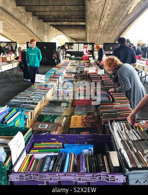 Flohmarkt Buch Stall mit Menschen auf die Bücher, die auf der Suche Am Ufer der Themse unter einer Brücke - London, Großbritannien Stockfoto