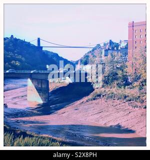 Ein Blick auf den Fluss Avon bei Ebbe, die Clifton Suspension Bridge in Bristol, England. Je näher der Kreuzung ist die Plimsoll Swing Bridge, und eine Anleihe Tabak Lager ist auf der rechten Seite. Stockfoto