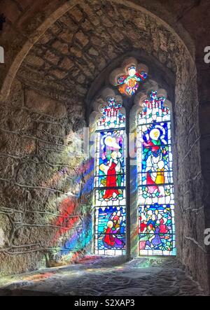 Glasfenster in der Kirche von St. Michael's Mount, Cornwall, UK mit dem Licht reflektieren auf die Mauer aus Stein Stockfoto