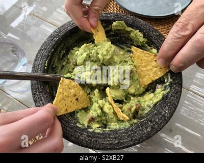 Tauchen Tortilla Chips in die Guacamole Stockfoto
