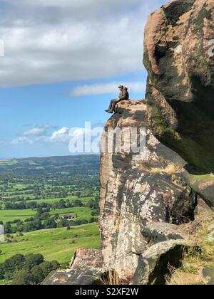 Männliche Wanderer sitzen auf einem Sandstein Felsformationen - Henne Cloud, Peak District National Park, Großbritannien Stockfoto