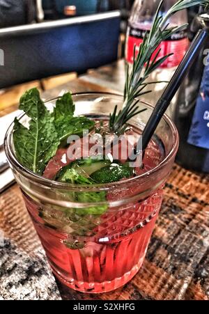 Pink Gin Tonic mit Erdbeeren pürieren, Minze, Gurke und ein Zweig Rosmarin Stockfoto