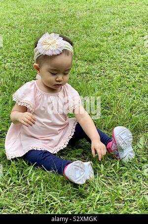 Babymädchen sitzen auf dem Rasen Stockfoto