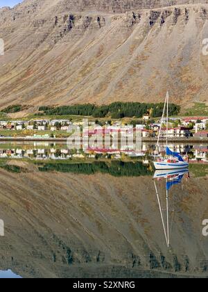 Isafjordur, Island - 26. September 2019: fantastisch hellen Reflexionen im Wasser auf einem warmen Herbst morgens Hafen. Stockfoto