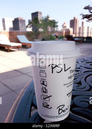 Nehmen Sie Tasse Starbucks pumpkin Spice latte auf einem Tisch in einem städtischen Dachterrasse Garten, NYC, USA Stockfoto