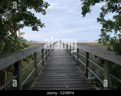 Lange hölzerne Seebrücke führenden zu Bucht Wasser mit Abend Himmel Stockfoto