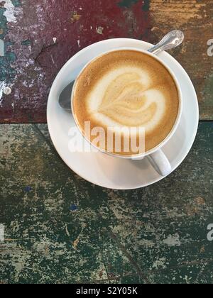 Schaumigen Espresso mit einem milchigen Herz flach von oben senkrecht mit kopieren. Weiße Tasse und Untertasse und Löffel. Stockfoto