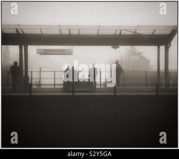 Pendler an Peckham Rye Bahnhof warten auf einem nebligen Morgen. Stockfoto