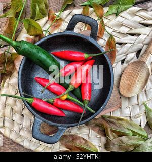 Rote und grüne Chilischoten in schwarzen gusseisernen Schüssel würzigen Gericht Stockfoto