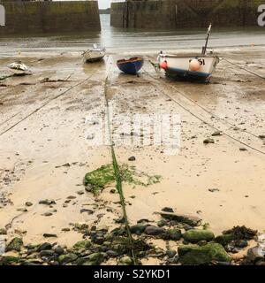 Kleine Boote im Mousehole Hafen bei Ebbe, November. Stockfoto