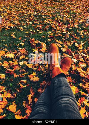 Entspannen im Herbst mit Frauen Beine gezeigt gekreuzt auf Blatt Boden Stockfoto