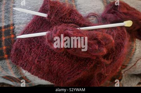 Knitting, a winter mohair sweater being made. Knitting, needles and wool on a checked blanket. Stockfoto