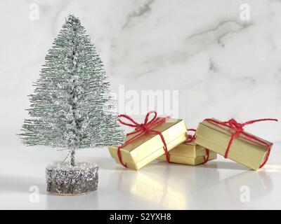 Miniatur Weihnachtsbaum mit Gold geschenkboxen gebunden mit roten Jute Stockfoto