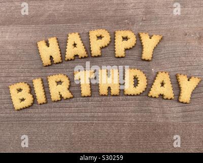 Alles Gute zum Geburtstag Text mit Keks Buchstaben auf einem Holzbrett Stockfoto