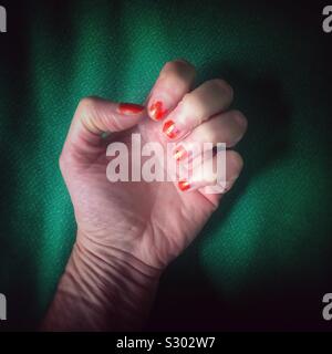 Woman's geballte Hand mit abgebrochenen orange Nagellack Stockfoto