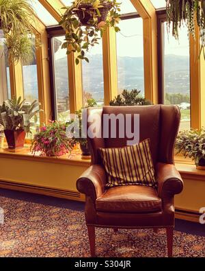 Einen bequemen Stuhl und Anlagen in der Nähe von Fenstern mit Blick auf die Landschaft in einem öffentlichen Bereich auf Trapp Family Lodge, Stowe, Vermont, United States Stockfoto