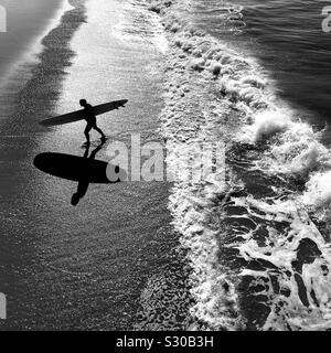 Männliche surfer Spaziergänge am Strand nach dem Surfen. Manhattan Beach, Kalifornien, USA.