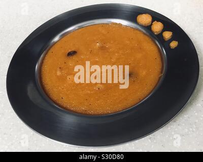 Kesari, einem indischen Nachtisch mit Grieß halwa mit Essen Farbe hinzugefügt Stockfoto