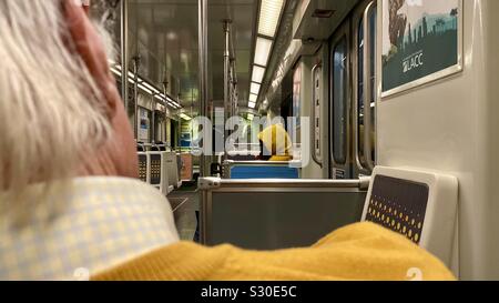 LOS ANGELES, Ca, November 2019: Blick über die Schulter der Mann in gelb Pullover, auf der Suche nach Person in gelb Hoodie, Reiten Die LA U-lila Linie U-Bahn Stockfoto