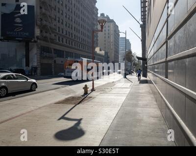 LOS ANGELES, Ca, November 2019: Morgen Ansicht mit langen Schatten entlang der Hill Street in der Innenstadt. Menschen wandern, LA Metro Bus- und Datenverkehr. Stockfoto