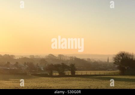 Eine misty Anfang Dezember morgen Blick nach Süden über Kirklees, West Yorkshire, UK. Das Foto zeigt die ehemaligen Ackerland, wo reiten Pferde jetzt grasen, und die lokalen Dorf und Pfarrei. Stockfoto