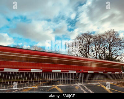 Ein South Western Railway Zug durch den Bahnübergang in Thames Ditton, Surrey, Stockfoto