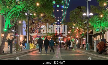 SANTA MONICA, CA, 15.12.2019: Holiday Lights und Fußgänger zu Fuß auf die 3rd Street in Downtown bei Nacht Stockfoto