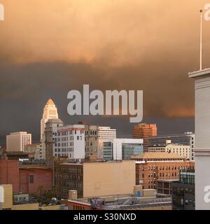 LOS ANGELES, Ca, DEZ 2019: Skyline der Innenstadt mit dem Rathaus im Hintergrund, leuchtet orange durch dramatische Wolken bei Sonnenuntergang Stockfoto