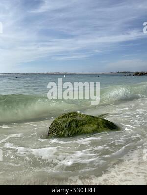 Große bemoosten Felsen am Strand Küste mit Wellen in Rollen Stockfoto