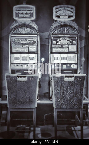 Zwei leere Stühle vor Spielautomaten im Casino nummeriert 12. und 14. Stockfoto