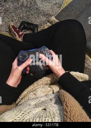 Frau sitzt auf dem Boden mit einer PlayStation cotroller Stockfoto