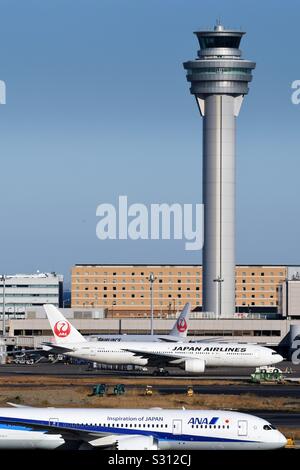 Flugzeuge auf dem Vorfeld mit den Tower im Hintergrund am Flughafen Haneda, Tokio. Stockfoto