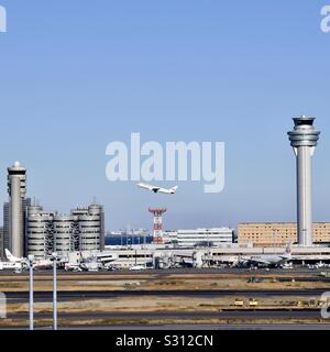 Flugzeuge, die über Control Tower und den Terminals am Flughafen Haneda in Tokio, Japan. Stockfoto