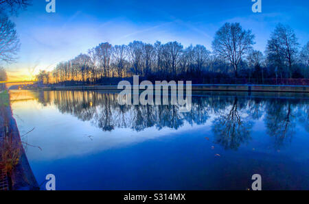 Tief blauen Himmel mit einem frühen aufgehenden Sonne im Wasser eines Flusses wider Stockfoto