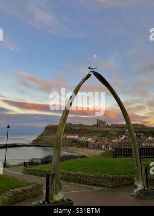 Walknochen arch am West Cliff von Whitby. Whitby Abbey zu sehen durch den Bogen und der Mond ist hoch in den Himmel über dem whalebones bei Sonnenuntergang Stockfoto