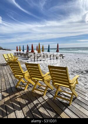 Sitzplatz im Freien am weißen Sandstrand mit bunten Stühlen, Picknickbänken und Sonnenschirmen Stockfoto