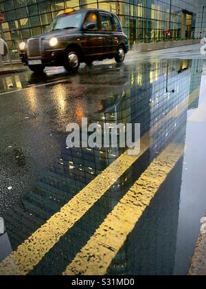 Black Cab an einem regnerischen Tag in Canary Wharf mit zweigelben Linien Stockfoto